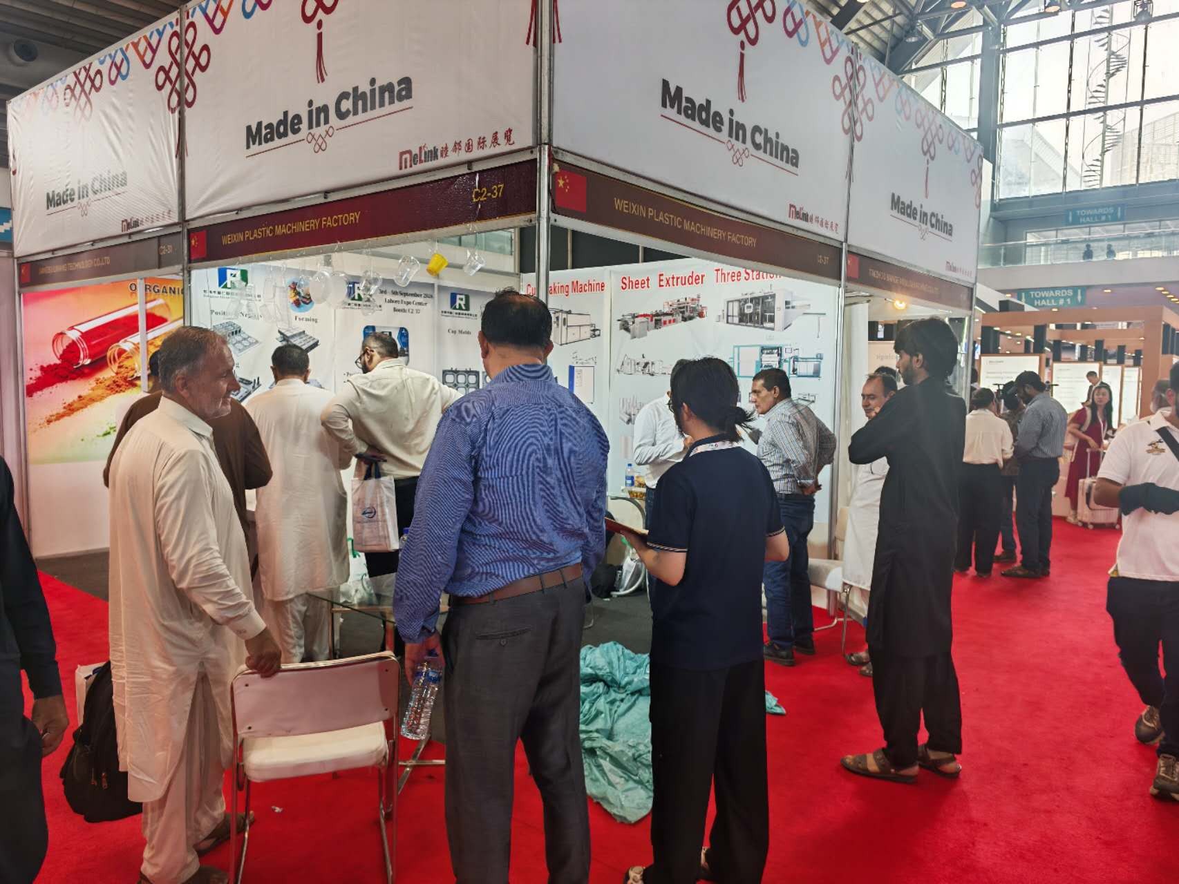 Buyers seated at the VihoX booth table examining formed PP cup samples at 3P Plas Print Pack Pakistan 2026