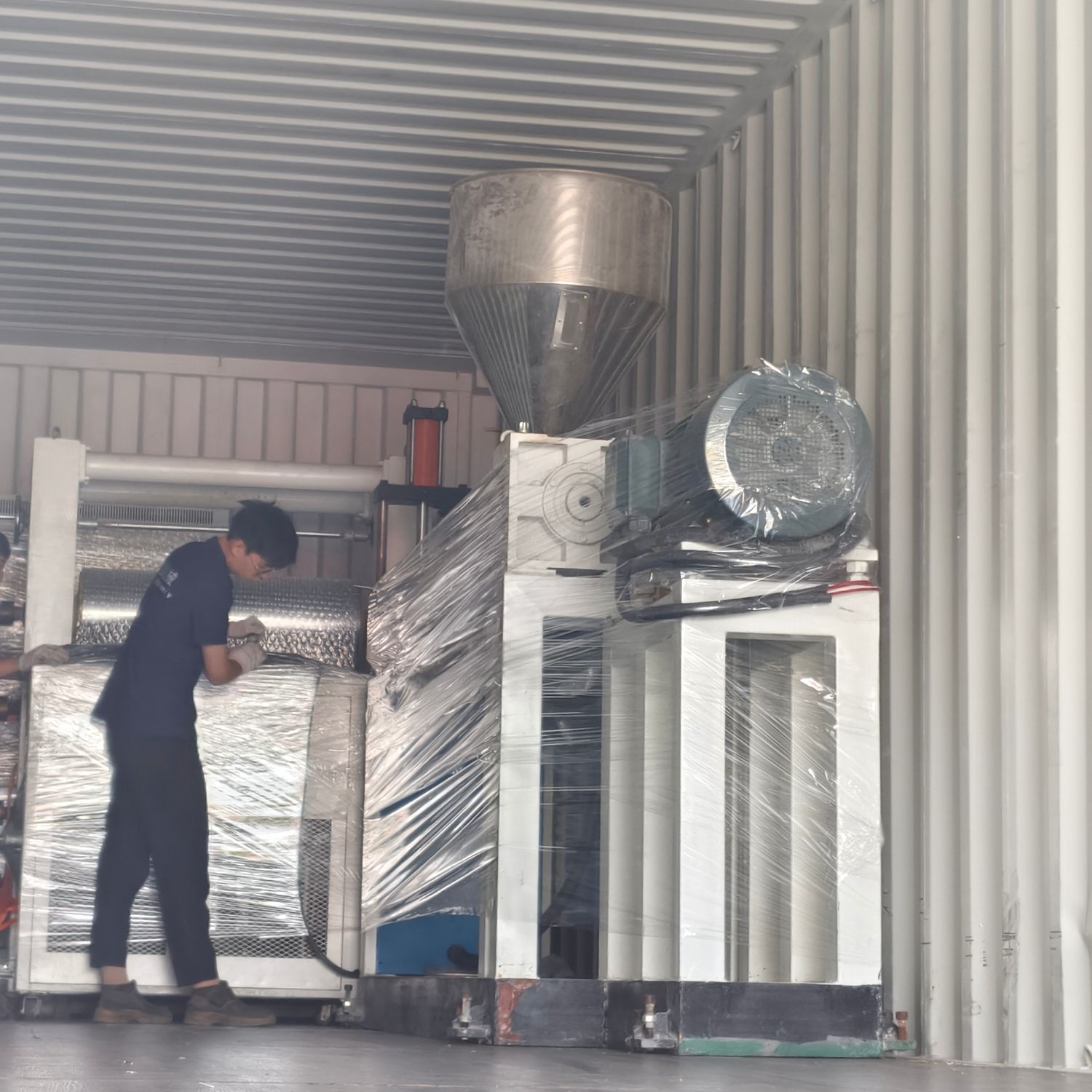 Worker wrapping a sheet extrusion line inside the container during loading