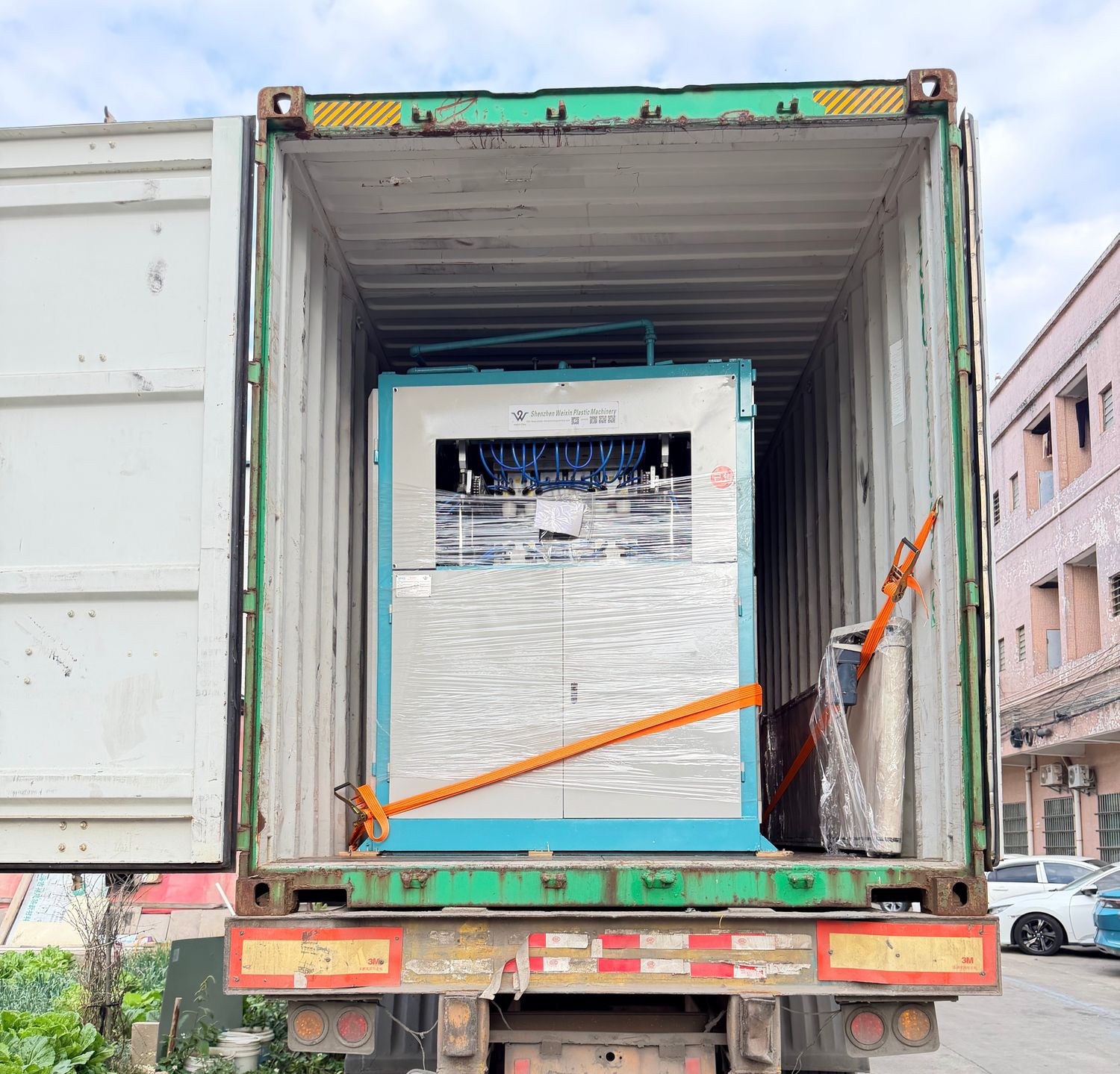 Diagonal ratchet strap anchoring a machine to the container structure